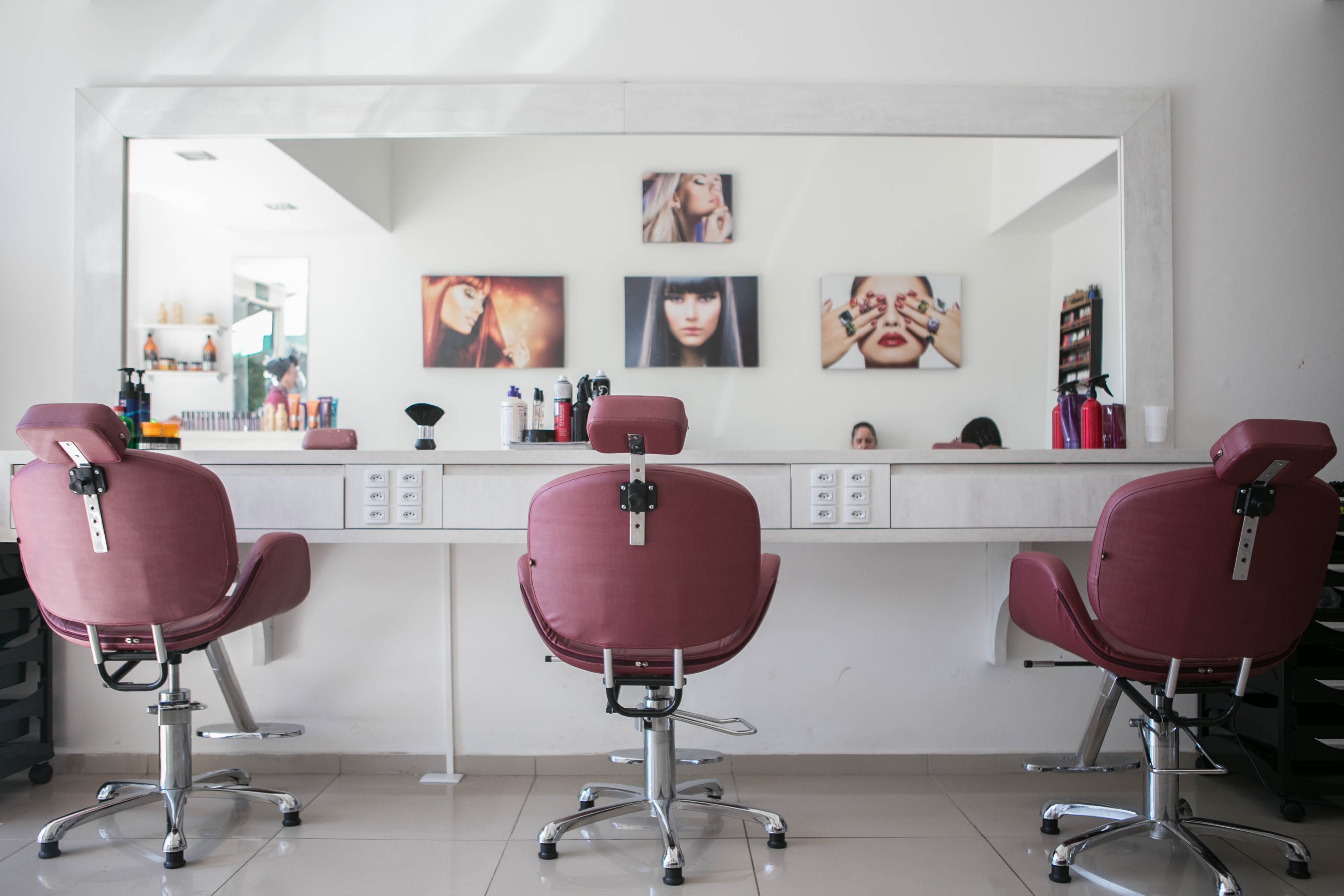 Three chairs for hairstyling facing mirror and workstation